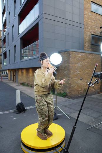 The same singer on the yellow booth, mic in hand, with flats behind