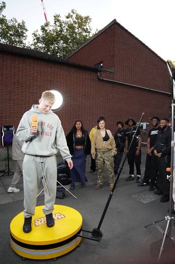 An artist in a grey tracksuit on the booth, the crowd lined up behind