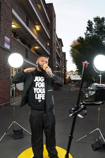An artist in a Jugg For Your Life T-shirt performing between two lights