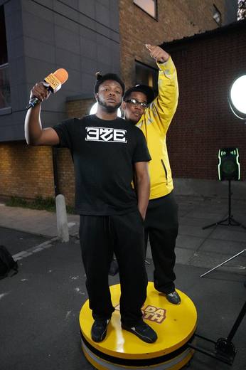 Two artists on the booth, one with his arm raised